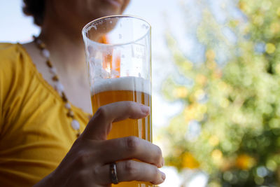 Midsection of woman holding beer at backyard