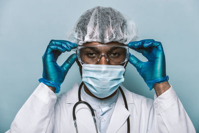 Close-up portrait of doctor against colored background