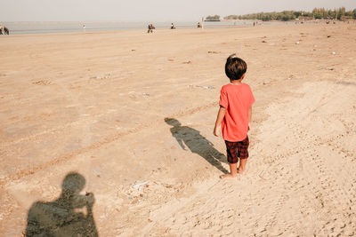 Rear view of child standing on the beach