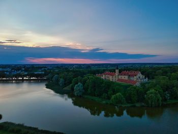 Scenic view of river by buildings against sky during sunset