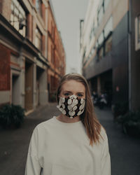 Portrait of young woman wearing mask standing outdoors