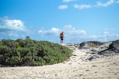 Rear view of person standing on land against sky