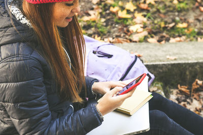 Girl sitting in the park using smartphone. teen using mobile phone, chat with friends and classmates