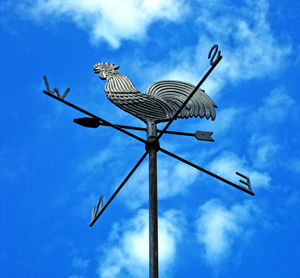 Low angle view of weather vane against blue sky