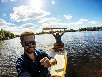 Portrait of male friends in boat on lake against sky