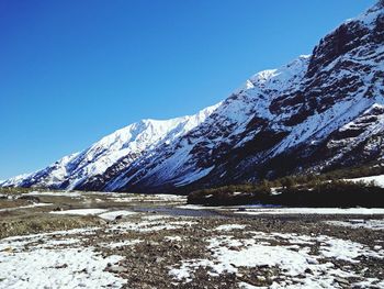 Scenic view of snowcapped mountains against clear blue sky