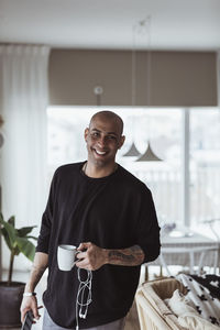 Portrait of smiling man with coffee mug in living room