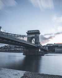 Bridge over river against cloudy sky