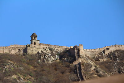Low angle view of fort against clear blue sky