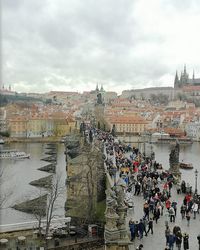 Group of people in city by river against sky