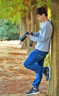 Man photographing against tree in forest