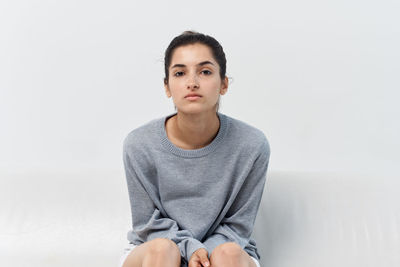 Portrait of teenage girl sitting against white background