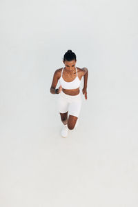 Portrait of young woman standing against white background