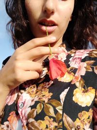 Close-up portrait of woman holding a poppy flower in her mouth