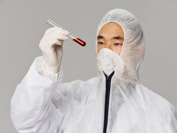 Midsection of doctor holding dentures against white background