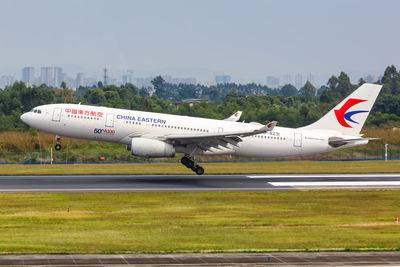 Airplane flying over airport runway against sky