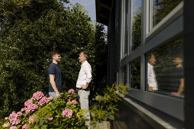 Son and father talking while standing at backyard