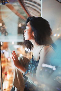 Portrait of woman looking through glass window