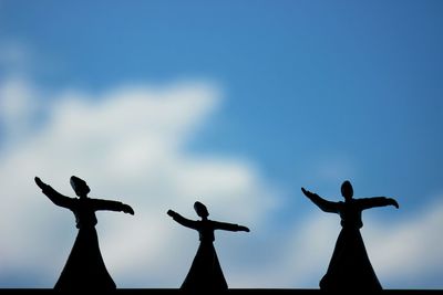 Low angle view of figurines against blue sky