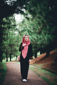 Portrait of woman standing by tree