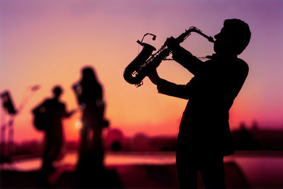 Silhouette twilight scene of saxophone man showing as trio musicians