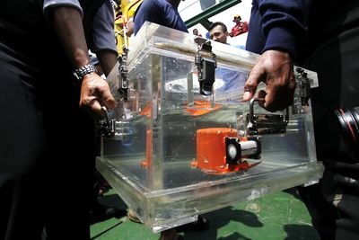 Cropped image of manual workers holding glass container in factory