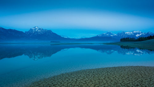 Scenic view of lake and mountains against blue sky