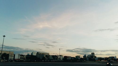 View of city at waterfront against cloudy sky