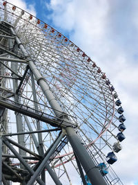 Low angle view of ferris wheel against cloudy sky