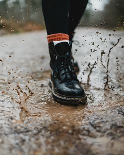 Low section of person standing on wet mud