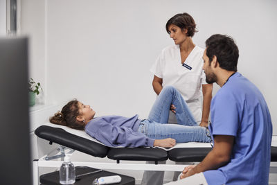 Doctors examining girl patient's leg during appointment