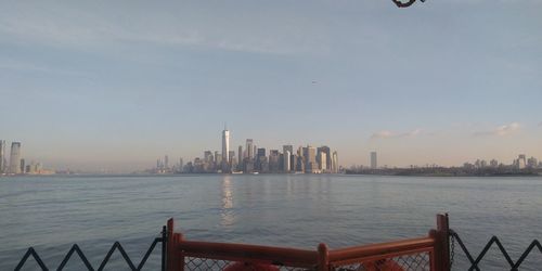 Sea and buildings in city against sky