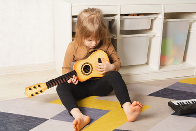 Child at home learning to play the guitar. leisure and education at home. 