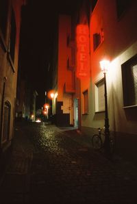 Illuminated street amidst buildings in city at night