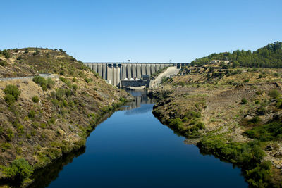 Arch bridge over river against clear blue sky