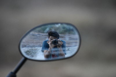 Man reflecting in side-view mirror of motorcycle