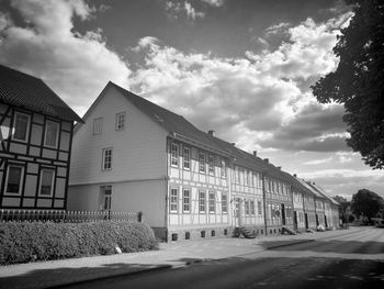 Empty road by building against sky