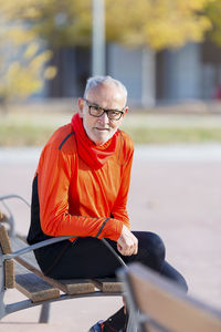 Portrait of senior man sitting on bench in park