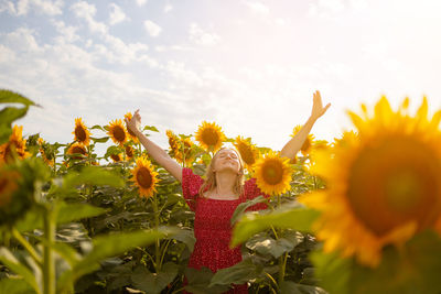 Low angle view of woman standing on sunflower against sky