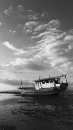 Boat moored on beach against sky