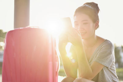 Smiling woman using smart phone with luggage