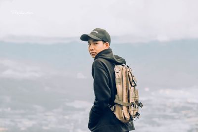 Man looking at camera against sky during winter