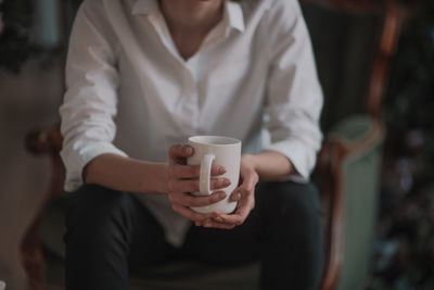 Midsection of woman holding coffee cup