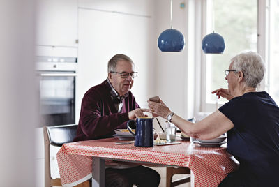 Full length of senior couple eating food at dining table