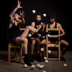 Young jugglers sitting on chairs with balls on stage