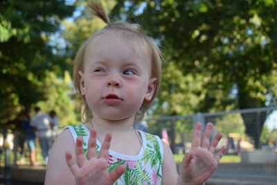 Close-up of girl making face against trees at park