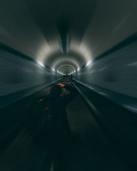 Rear view of man photographing while standing in tunnel
