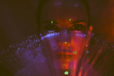 Portrait of beautiful young woman against illuminated background