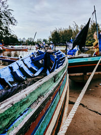 Fishing boats moored at harbor against sky