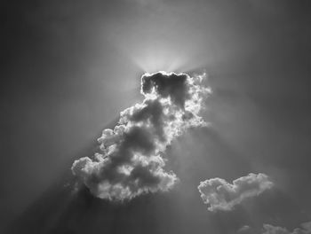 Low angle view of sunlight streaming through clouds